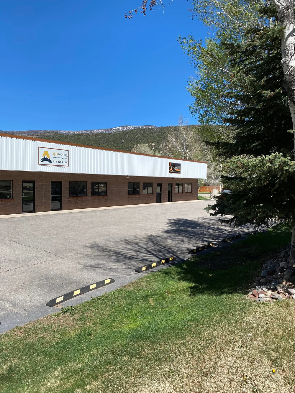 Front of the Basalt mixed use building with tenant doors and windows, a landscaped lawn and mountain views behind it