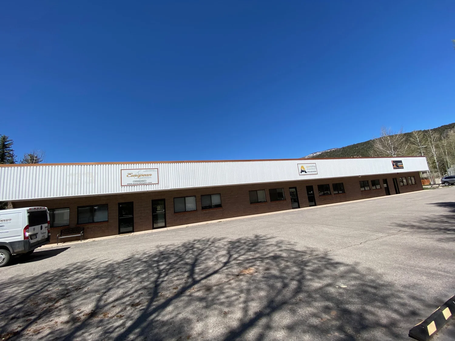 Wide view of the single story mixed use building on Park Ave in Basalt, with tenant doors, windows and a full length parking lot in front